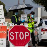 A Testing Center specialists with personal protective equipment (PPE) assist drivers at a drive-in Covid-19 testing site in south Los Angeles, California on November 14, 2020. - After California passed 1 million coronavirus cases a travel advisory was issued on November 13 urging a two-week quarantine for those arriving from other states or countries. (Photo by Apu GOMES / AFP) (Photo by APU GOMES/AFP via Getty Images)