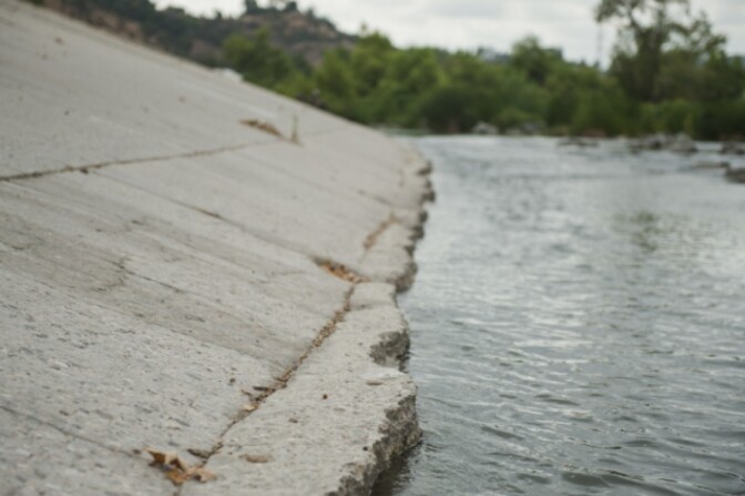 The Los Angeles River flows through the Frogtown neighborhood in Los Angeles, California. The river's banks are mostly concrete. 