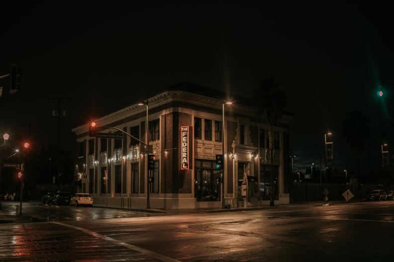 A stately building called The Federal on an LA street corner at night, illuminated by street lights