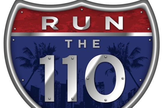 A freeway shield sign that reads Run the 110 with palm trees and the city skyline in the background.