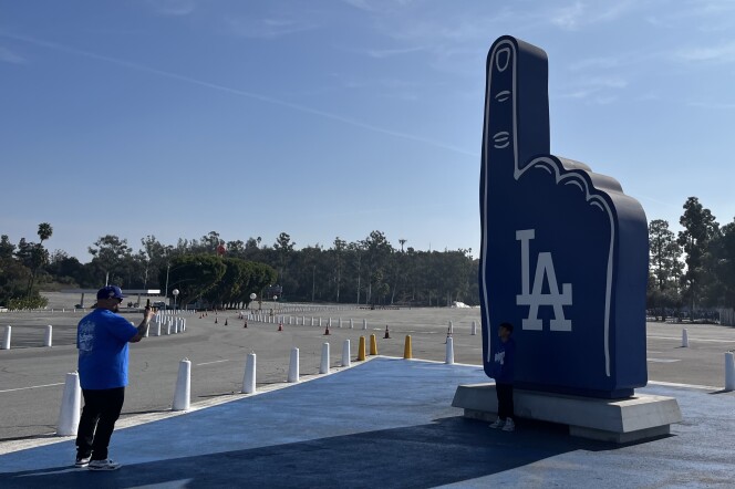 A man takes a photo of a giant replica of a Dodgers foam finger. 