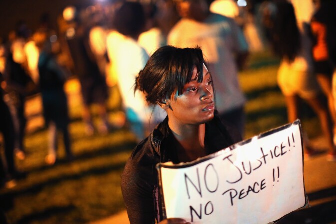 ST. LOUIS, MO - AUGUST 12:  Demonstrators protest the killing of teenager Michael Brown outside Greater St. Marks Family Church while Brown’s family along with civil rights leader Rev. Al Sharpton and a capacity crowd of guests met inside to discuss the killing on August 12, 2014 in St Louis, Missouri. Brown was shot and killed by a police officer on Saturday in the nearby suburb of Ferguson. Ferguson has experienced two days of violent protests since the killing but, tonight the town remained mostly peaceful.  (Photo by Scott Olson/Getty Images)