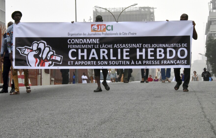 People hold a banner of the Organization of Ivorian Professional Journalists, firmly condemning the slaying of journalists in France, on January 11, 2015 as they march toward the French embassy in Abidjan in tribute to the 17 victims of the three-day killing spree in Paris. The killings began on January 7 in Paris with an assault on the Charlie Hebdo satirical magazine in Paris that saw two brothers killing 12 people, including some of the country's best-known cartoonists, and the storming of a Jewish supermarket on the eastern edge of the capital, which killed four local residents. 