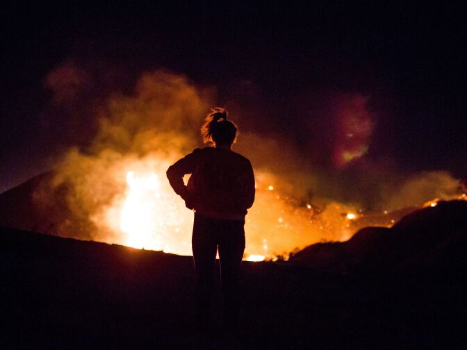 A resident watches as the Creek Fire burns along a hillside near homes in the Shadow Hills neighborhood of Los Angeles on Dec. 5, 2017.