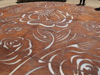 A steel art project titled "Sobrevivir" features flowers representing fertility and offerings and a set of hands symbolic of the Virgen de Guadalupe.