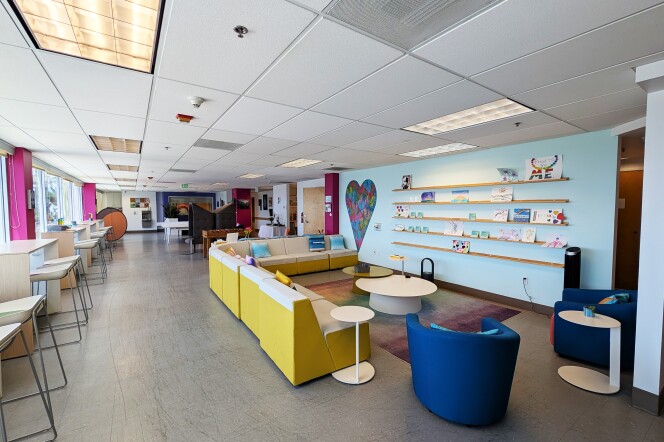 The interior of the allcove Beach Cities mental health center in Redondo Beach. There is a light blue wall surrounded by couches, chairs and tables. 