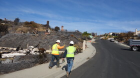 Contractors hike up a steep street in the Clearpoint neighborhood of Ventura, capping gas lines at homes that burned in the Thomas Fire.