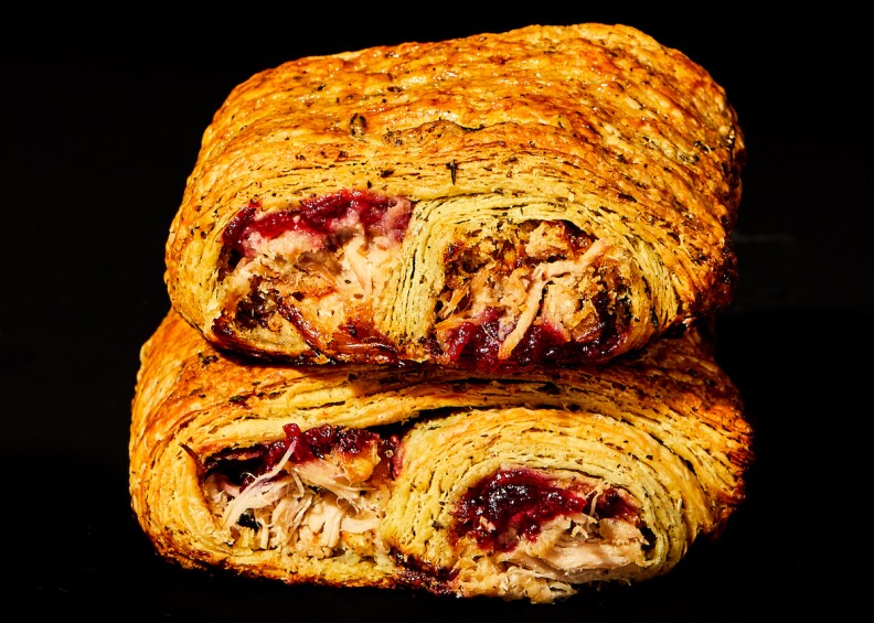 two croissants are stacked on top of each other. they are both filled with meat and red jam