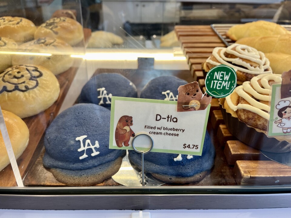 A photo of pastries shaped like blue Dodger helmets are arranged behind a glass case. 