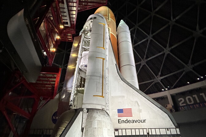 A space shuttle stands in it's launch position. A hatch on the shuttle is open. 