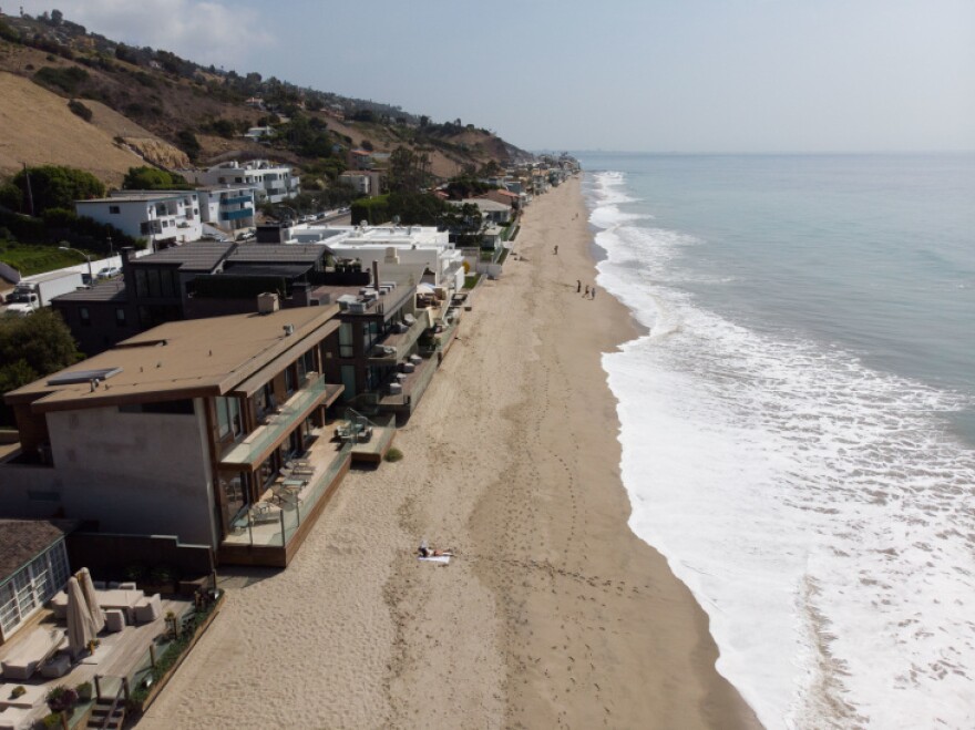 A beach with mansions perilously close to the water along a coastline in California.