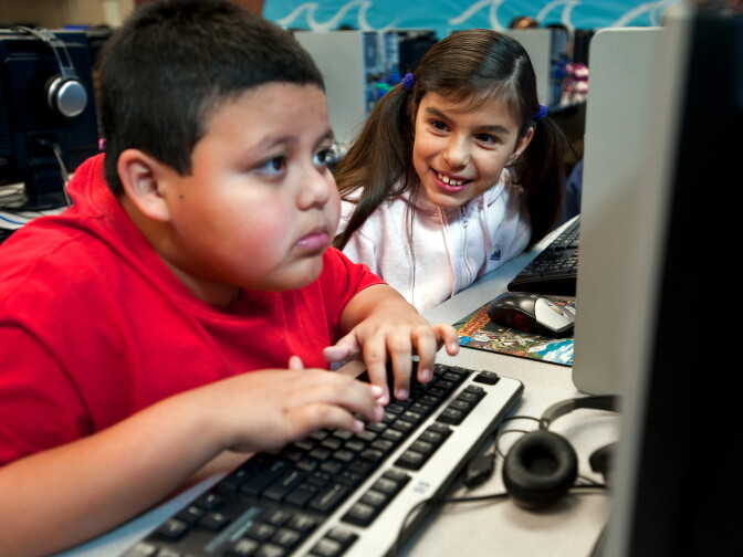 Third grader Natalia Garcia, left, helps her classmate, Efren Gonzalez, during a computer lab class on Wednesday morning.