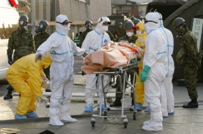 A person who is believed to be have been contaminated with radiation, wrapped with a blanket, is carried to ambulance at a radiation treatment centre in Nihonmatsu city in Fukushima prefecture on March 13, 2011.