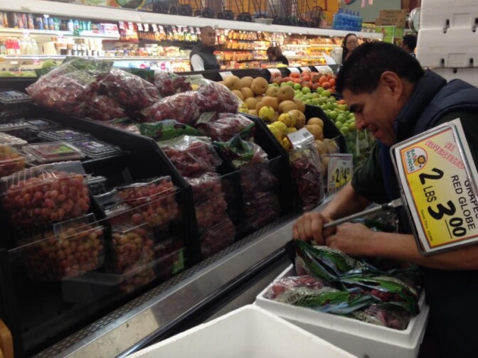 An employee at Baja Ranch supermarket stocks red grapes, big sellers with Latino customers for New Year's Eve. Eating 12 grapes at midnight for good luck is an old Spanish tradition, observed in much of Latin America.