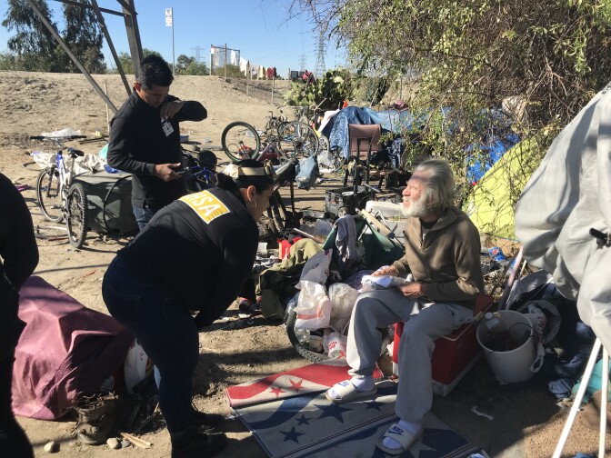 Outreach workers from the Los Angeles Homeless Services Authority speak to a homeless man living in an encampment in the San Gabriel River Valley in El Monte. 