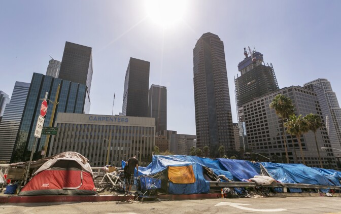 Tents used by the homeless line a downtown Los Angeles street with the skyline behind Tuesday, Sept. 22, 2015.