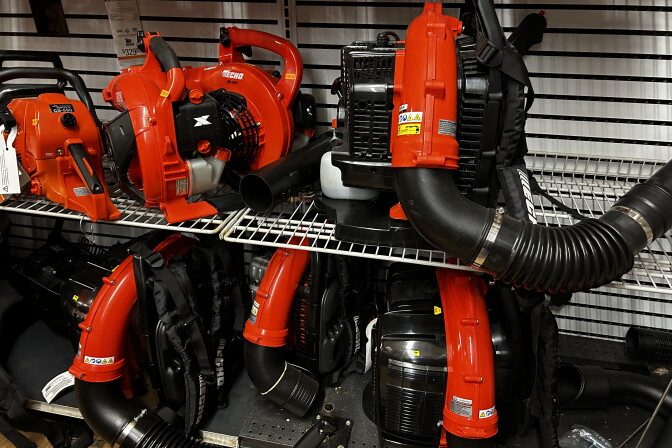 Five bright orange and black electric leaf blowers on a store shelf. 