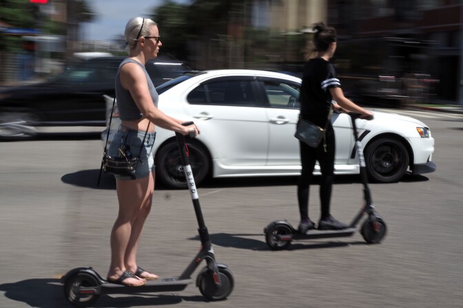 People ride shared electric scooters in Santa Monica, California, on July 13, 2018. - Cities across the U.S. are grappling with the growing trend of electric scooters which users can unlock with a smartphone app. Scooter startups including Bird and Lime allow riders to park them anywhere that doesn't block pedestrian walkways but residents in some cities, including Los Angeles, say they often litter sidewalks and can pose a danger to pedestrians. (Photo by Robyn Beck / AFP)        (Photo credit should read ROBYN BECK/AFP/Getty Images)