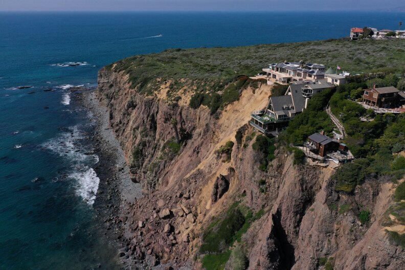 Homes on a cliffside that is crumbling into the ocean.
