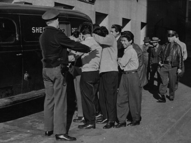  Police officers are shown on the way to court with a group of Mexican youth who assertedly took part in a gang war in which a 17-year-old boy suffered bullet and stab wounds. The youth were scheduled for arraignment on this day, Tuesday, March 27, 1945. 