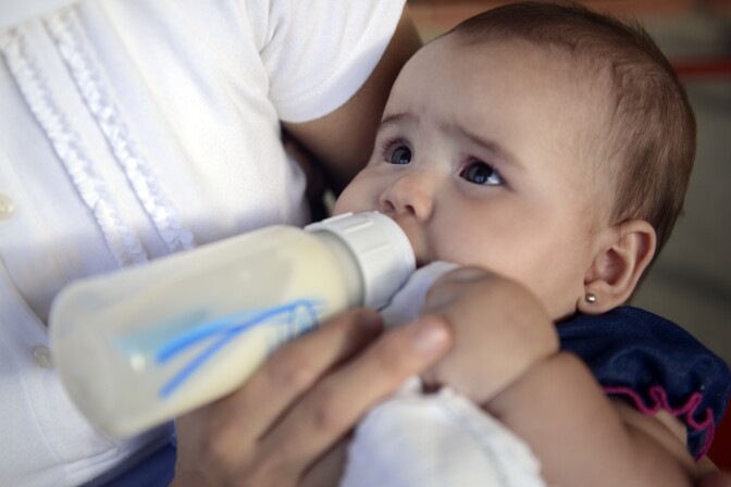 Woman feeds a baby with a bottle of breast milk.