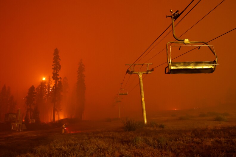 A chairlift at Sierra-at Tahoe ski resort sits idle as fire turns the sky red