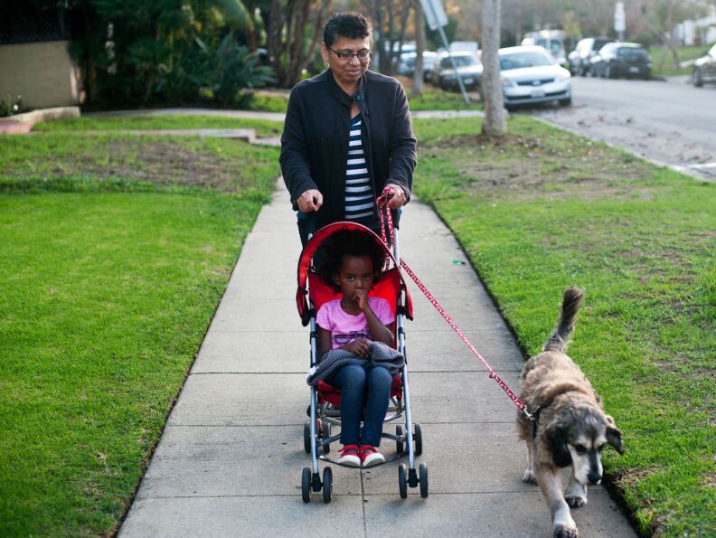 Nanny Delfina Recinos and Luli Schroeder walk the family's dog, Bailey, in the afternoon. Recinos helps Trista, a single mother, look after Luli after school.