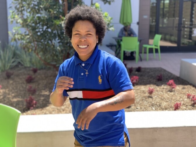 Jasmine Jones wears a blue polo shirt and a cross necklace in a photo taken outside.