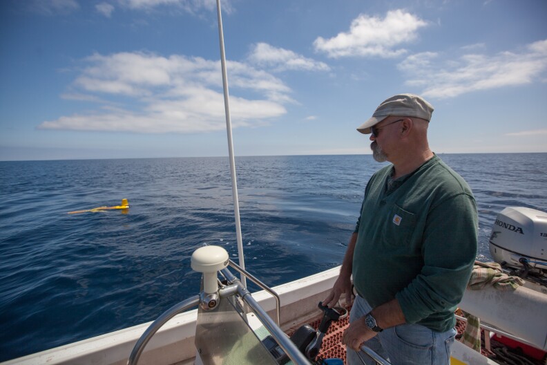 Carl Oberg, an engineering technician for the USC Robotics Research Lab, pilots a skiff around a submersible robot during preliminary testing on a two-week research mission.