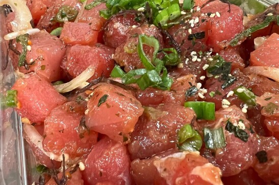 A try of Hawaiian-style ahi-tuna poke. The ahi tuna is red with cuts of garlic, onion and greens mixed in. 