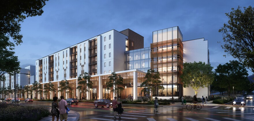 A rendering of what the new dorm will look like in the evening. The building is a mix of steel, glass, and wood. It is aglow with light from within, surrounded by small trees. People roam about, some in pairs. One is on a bicycle.