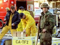 A California National Guard troop stands watch outside the Northridge Meadows Apartments, early Jan. 18, 1994 as rescue workers pack up gear. Sixteen people died in the apartment building, which collapsed after an earthquake registering 6.6 on the Richter scale hit the area.