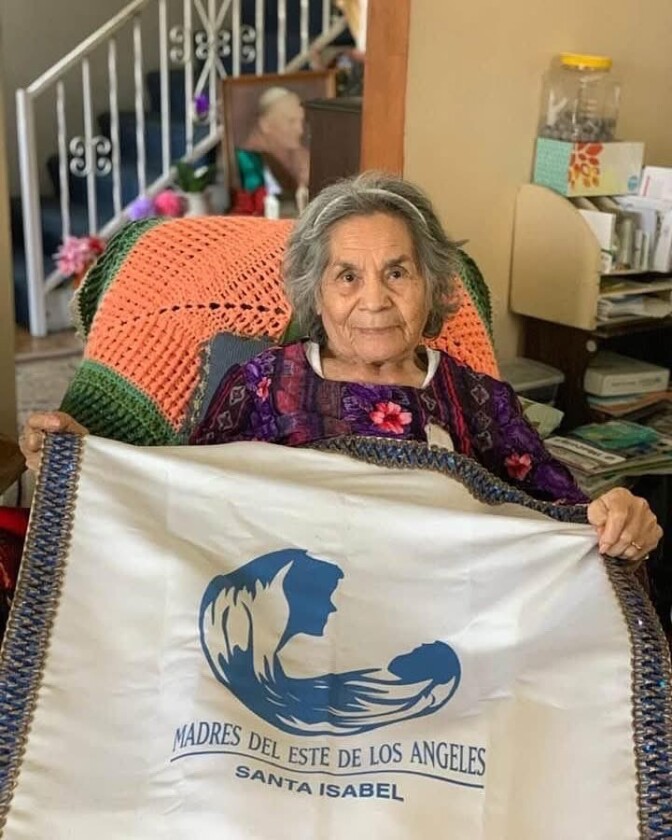 Elderly female presenting person with medium skin tone and gray hair holding a banner.