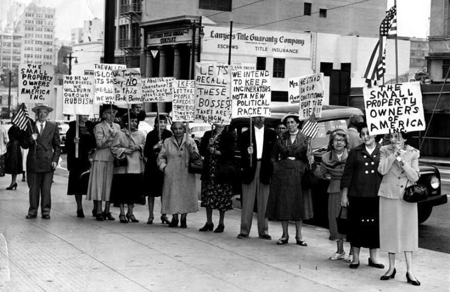 "Group photo of picketers holding plackards on the sidewalk. One of the signs reads, "No new pork barrel, we will burn our own rubbish," another reads, "We intend to keep incinerators, not a new political racket!" Photo dated: June 30, 1955." 