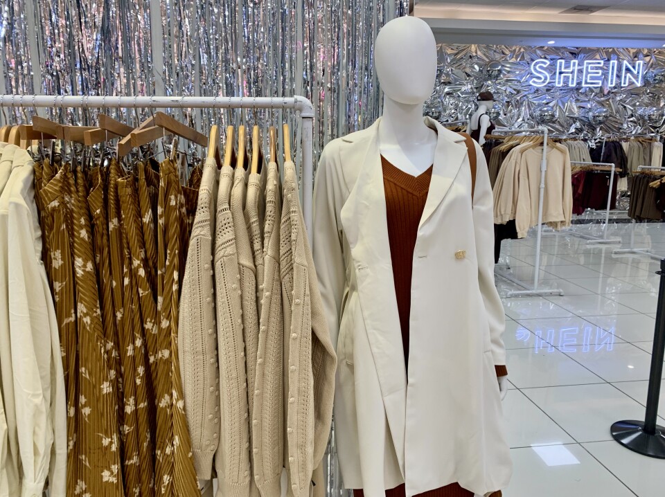 A rack of cream, beige and brown clothing, including a trenchcoat, sweaters and skirts.