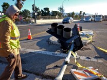 A Los Angeles Department of Transportation worker tends to a fallen traffic light that was blown down by heavy winds in the Van Nuys section of Los Angeles on Saturday, Jan. 24, 2015. A brief but powerful round of Santa Ana winds with gusts topping 60 mph toppled trees and power lines in Los Angeles. About 9,000 customers were without electricity in the San Fernando Valley Saturday morning.