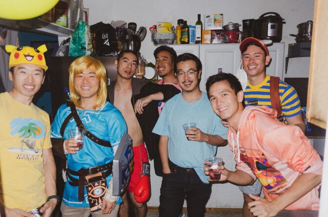 A group of Asian men pose in a kitchen for a photo.
