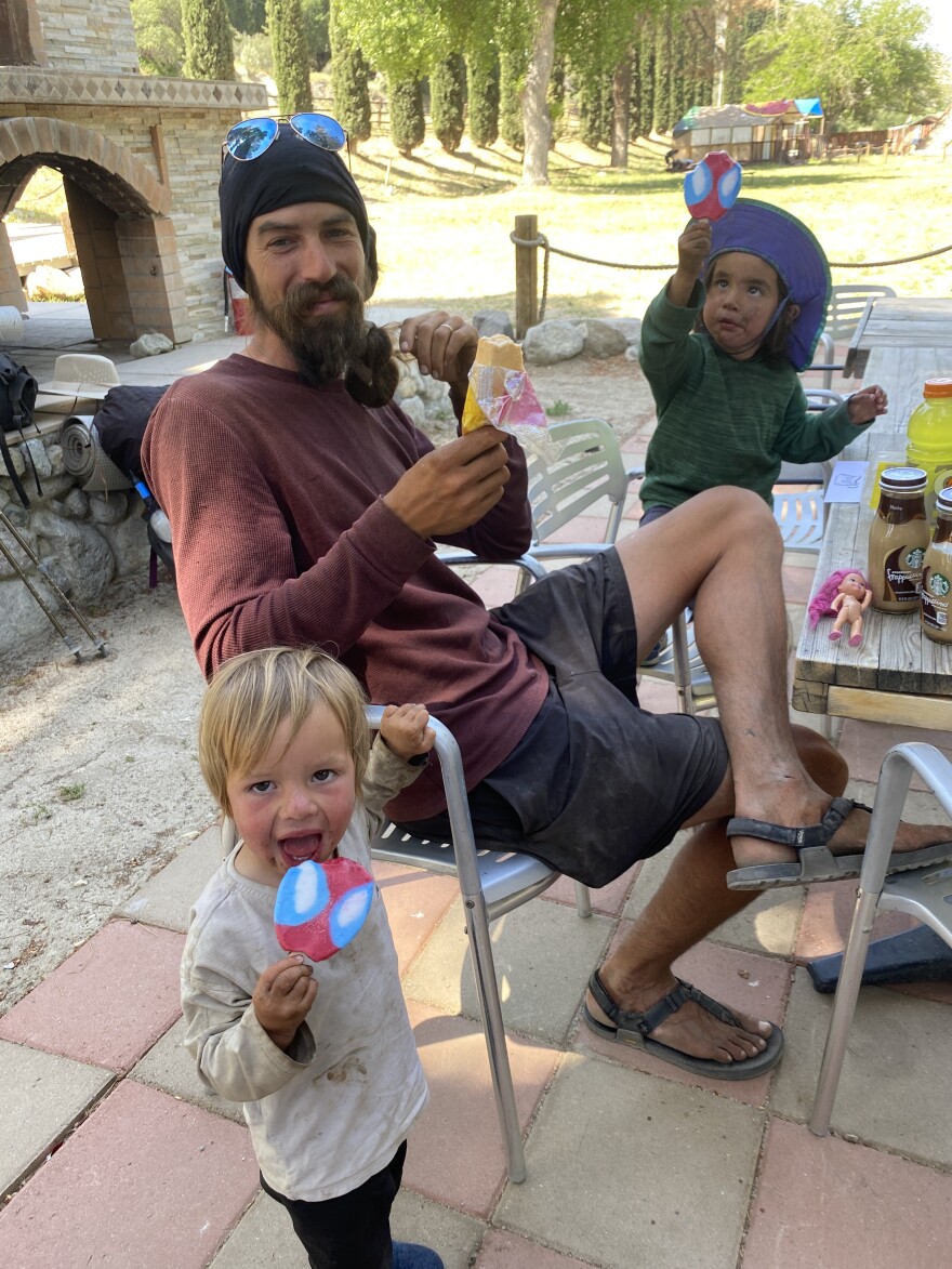 A man and two little boys eat popsicles.