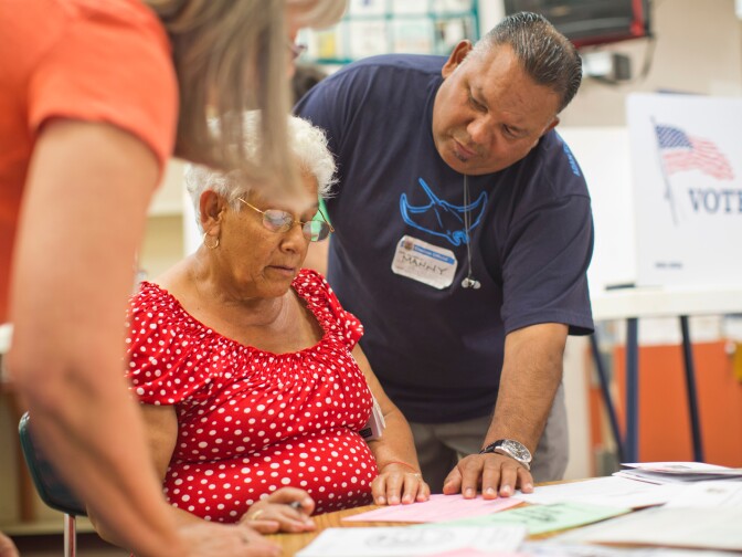 Poll clerk Manny Romero, right, helps translate for a Spanish-speaking voter at Canyon Springs School's library on Tuesday evening, June 3 in Santa Clarita during Los Angeles County's primary election.