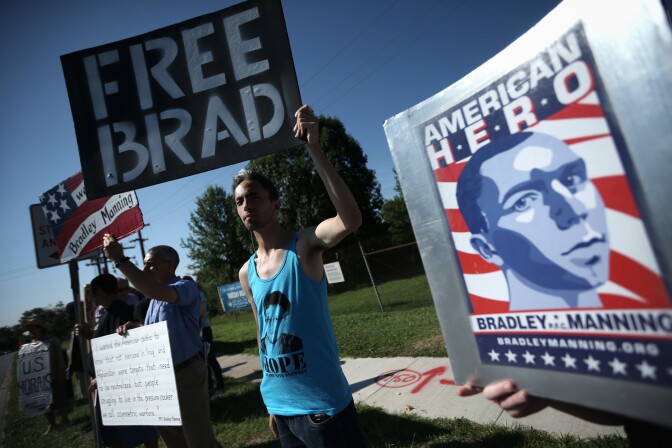 Yoni Miller (R) of Social Movement Technologies, along with other supporters of U.S. Army Pfc. Bradley E. Manning, hold signs to show support during a demonstration outside the main gate of Ft. Meade on July 30, 2013 in Maryland.