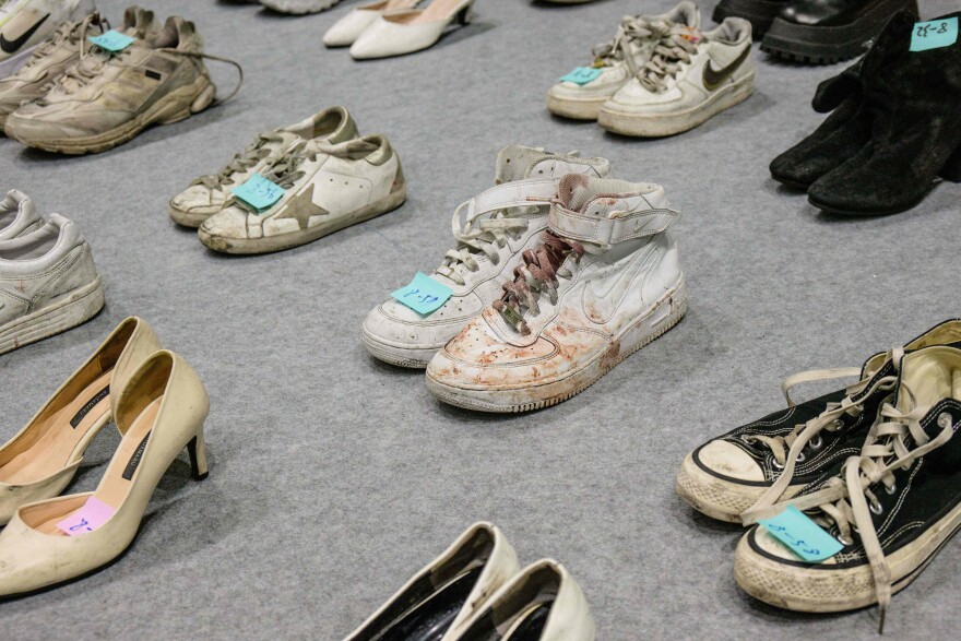 Blood tainted shoes are placed by pairs in rows.