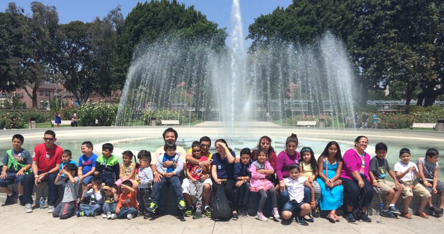 Janitors and their children at the Rose Garden fountain outside the California Science Center. The families attended a field trip on Sunday May 3, 2015, as part of an initiative by the UCLA Labor center and the janitor's union, SEIU United Service Worker's West to help janitors better understand the benefits of early education and navigate the system.