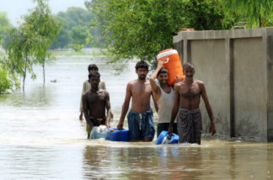 Pakistani flood survivors return to higher ground after getting drinking water in the flooded area of Pathan Wala on August 16, 2010